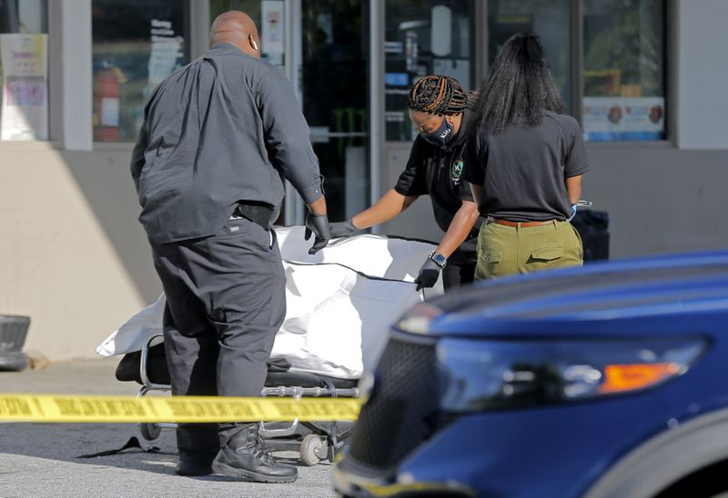 A body is removed from the scene of a shooting in the parking lot of a Chevron station.