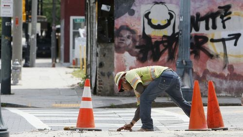 A worker does maintenance on a sidewalk along Auburn Avenue in Atlanta. (BOB ANDRES / ROBERT.ANDRES@AJC.COM)