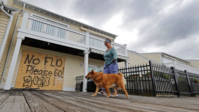 Barbara Timberlake walks with her dog Danny past a boarded up store on the river front in downtown Wilmington, N.C., as Hurricane Florence threatens the coast Thursday, Sept. 13, 2018. A store in South Carolina offered shoppers half priced frozen foods and meat ahead of the storm.