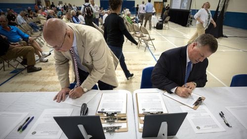 Two Glynn County residents fill out comment cards during a public hearing in April 2018 to discuss the Federal Aviation Administration’s recently released environmental impact study about the potential site for a spaceport in Kingsland. (AJC file photo)