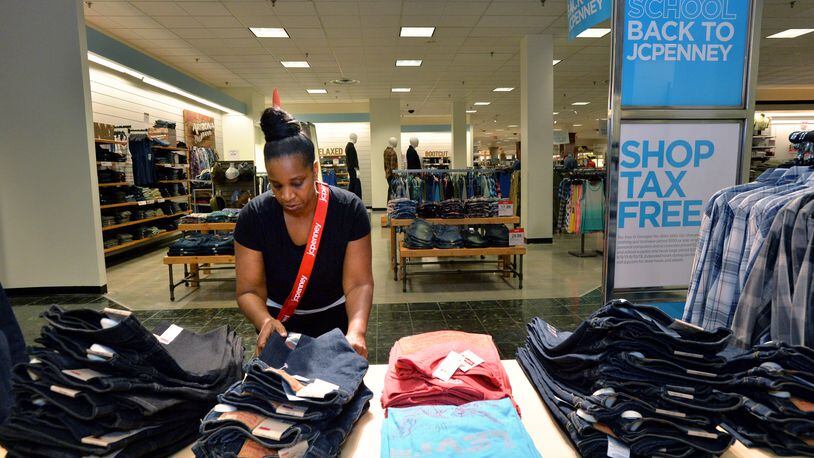 Tammy Wright, support specialist, arranges a display of clothing before the store opens during the sales tax holiday in 2013 HYOSUB SHIN / HSHIN@AJC.COM