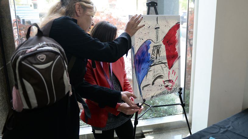 NOV. 16, 2015 ATLANTA Artist Florence Beauredon arranges a painting in honor of the Paris attacks. A crowd of about 400 people gathered at the French Consulate in Atlanta on Sunday, during a rally in support of the victims of the Paris terrorist attack.After brief remarks the crowd sang “La Marseillaise,” the French national anthem. KENT D. JOHNSON/KDJOHNSON@AJC.COM