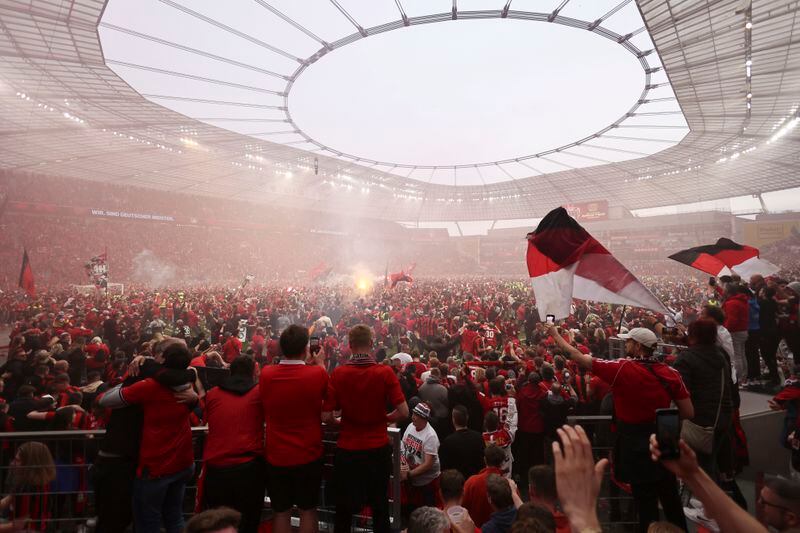 Leverkusen fans run onto the pitch to celebrate their team winning the Bundesliga after the Bundesliga soccer match between Bayer Leverkusen and Werder Bremen at the BayArena in Leverkusen, Germany, Sunday April 14, 2024. (Rolf Vennenbernd/dpa via AP)