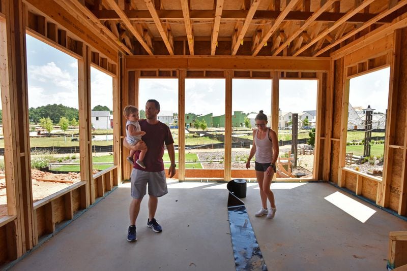 Spenser and Cory Hewett check the construction of their new house as Cory holds his 15-month-old son Eliot in the Pinewood Forest community in Fayetteville on Saturday, June 22, 2019. Spenser and Cory Hewett are millennials who have left their life in Buckhead for Fayette County, metro Atlanta’s oldest county by age. HYOSUB SHIN / HSHIN@AJC.COM