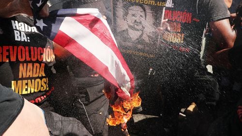 A group tries to burn an American Flag as police move in near the sight of the Republican National Convention (RNC) in downtown Cleveland on the third day of the convention on July 20, 2016 in Cleveland, Ohio. Many people have stayed away from downtown due to road closures and the fear of violence. (Photo by Spencer Platt/Getty Images)