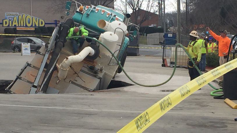A worker climbs on a truck that is stuck in a sinkhole in Hall County. (Credit: Channel 2 Action News)