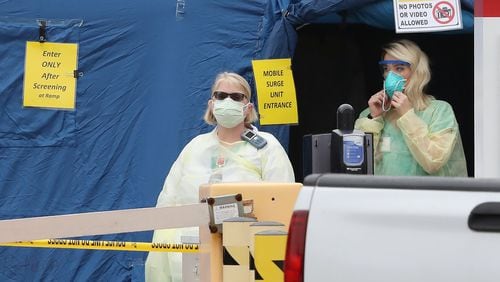 Medical workers at the entrance to the mobile surge unit tent for coronavirus testing outside the emergency entrance at WellStar Kennestone Hospital in Marietta on Tuesday, March 17. Curtis Compton ccompton@ajc.com