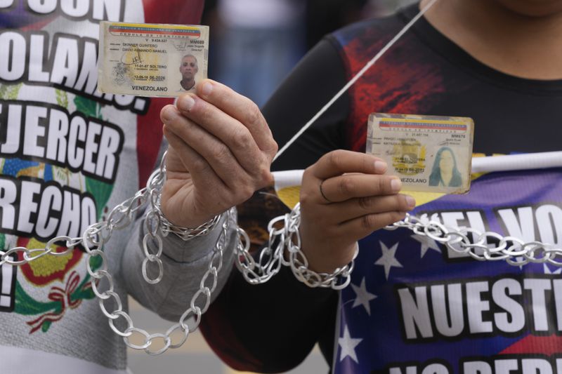 Venezuelans wanting to vote in their upcoming presidential elections hold up their national ID cards as they protest against what they perceive as complicated voting requirements outside their embassy in Lima, Peru, Monday, April 15, 2024. (AP Photo/Martin Mejia)
