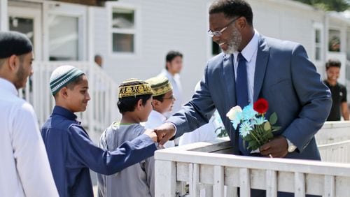 George Lanier (right), pastor of Grace United Methodist Church in Covington, fist-bumps with students at the Masjid At-Taqwa Mosque in Doraville as he is welcomed with flowers on Tuesday, Aug. 23, 2016. BOB ANDRES /BANDRES@AJC.COM