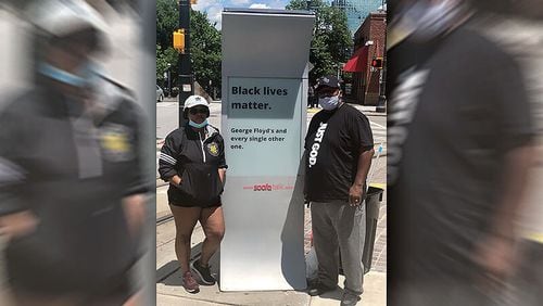 Sakeema Freeman and her father Veree got to work Saturday morning cleaning graffiti off of a sign in downtown Atlanta after a night of violence. GREG BLUESTEIN/STAFF