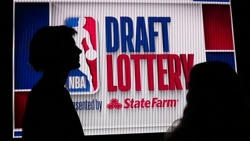 NBA basketball draft prospect Johnny Furphy, left, looks at the draft lottery order in front of a draft lottery sign before the draft lottery in Chicago, Sunday, May 12, 2024. (AP Photo/Nam Y. Huh)