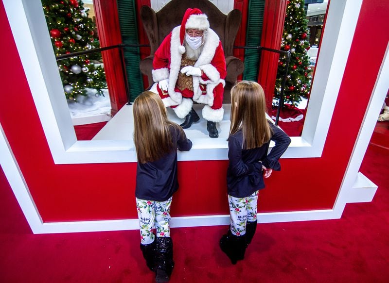 Brooklynn McCarty, 8, (L) and her twin sister Madison, 8, talk with Santa Clause at the Perimeter Mall Sunday, November 22, 2020   STEVE SCHAEFER / SPECIAL TO THE AJC 