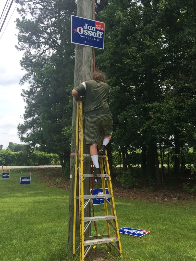 Mike Waters removes a Jon Ossoff sign from a utility pole in his daughter, Chelsea Clements, yard earlier this week.