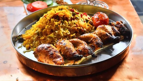 Zafron's Joojeh Kabob (Cornish hens), shown with the restaurant’s popular Jeweled Rice and grilled plum tomatoes. (Chris Hunt for The Atlanta Journal-Constitution)