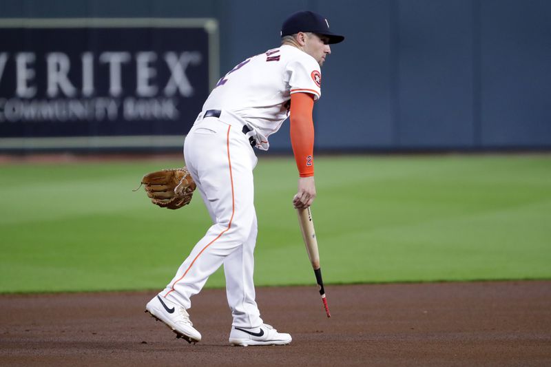 Houston Astros third baseman Alex Bregman picks up the barrel of Atlanta Braves' Ronald Acuña Jr. broken bat from the baseline during the first inning of a baseball game Tuesday, April 16, 2024, in Houston. (AP Photo/Michael Wyke)