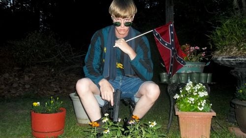 This undated image that appeared on Lastrhodesian.com, a website being investigated by the FBI in connection with Charleston, S.C., shooting suspect Dylann Roof, shows Roof posing for a photo while holding a Confederate battle flag. The website surfaced online Saturday, and also contained a hate-filled 2,500-word essay that talks about white supremacy and concludes by saying the author alone will need to take action. (Lastrhodesian.com via AP)