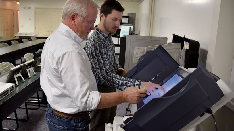 Merle King (left), the executive director of the Center for Election Systems at Kennesaw State University, and Steven Dean, the technical coordinator, review the setup procedure of a voting machine. The center outsources repairs to Georgia’s 27,000 voting machines but is responsible to testing each unit before it is put back into service. BRANT SANDERLIN/BSANDERLIN@AJC.COM