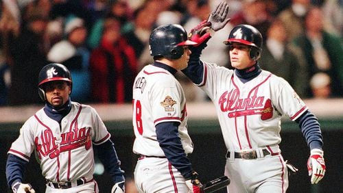 Chipper Jones (right) celebrates with teammates Ryan Klesko and Luis Polonia after scoring on a hit by David Justice in the seventh inning of Game Four of the 1995 World Series.