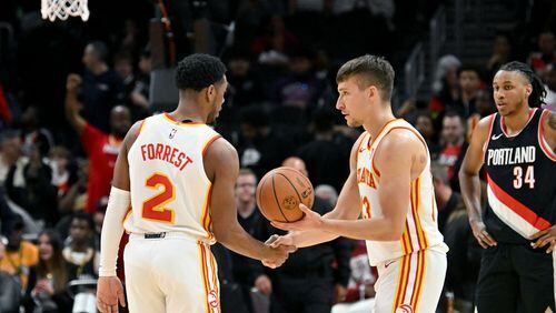 Hawks guard Trent Forrest (left) and guard Bogdan Bogdanovic shake hands at the end of the fourth quarter of an NBA basketball game at State Farm Arena, Wednesday, March 27, 2024, in Atlanta. The Hawks won 120-106 over the Portland Trail Blazers. (Hyosub Shin / Hyosub.Shin@ajc.com)