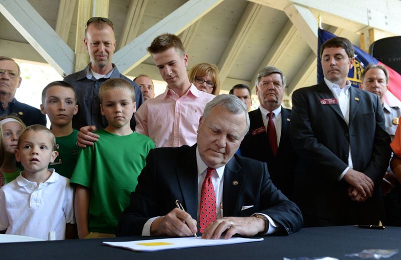 Governor Nathan Deal signs the BUI, boating under the influence, bill at Lake Lanier as family and friends of Jake and Griffin Prince and lawmakers stand behind him on Tuesday, April 23, 2013.