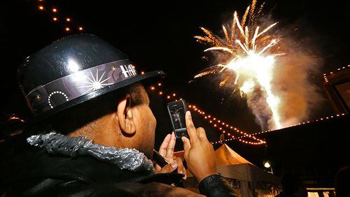Mike Snipes of Atlanta snaps photos of the fireworks as 2014 arrives Wednesday at the Peach Drop at Underground Atlanta Jan.1, 2014, in Atlanta.