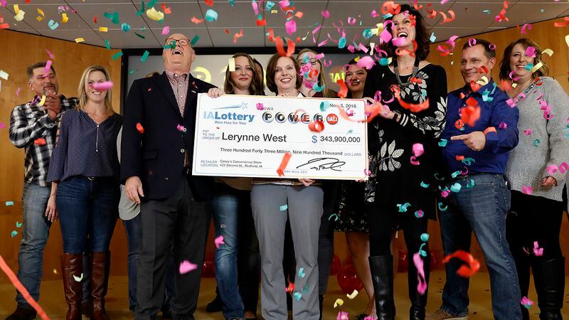 Iowa Lottery CEO Terry Rich, left, presents a check to Lerynne West, of Redfield, Iowa, center, for her share of a nearly $700 million Powerball prize, Monday, Nov. 5, 2018, at the Iowa Lottery headquarters in Clive, Iowa. West was one of two winners of a $688 million jackpot drawn Oct. 27. She'll share the prize with someone who bought the other winning ticket in New York City.