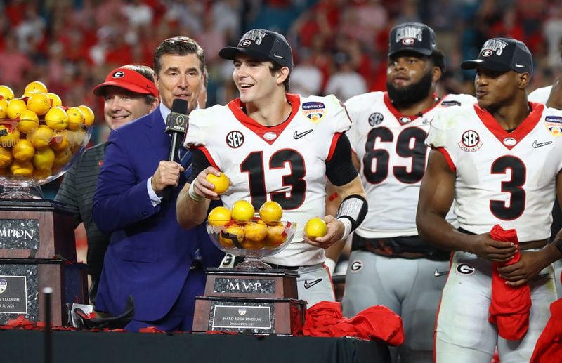 Georgia quarterback Stetson Bennett, tosses oranges to teammates as he is awarded the trophy after beating Michigan 34-11 to win the Orange Bowl at Hard Rock Stadium on Friday, Dec. 31, 2021, in Miami Gardens.     Curtis Compton / Curtis.Compton@ajc.com 