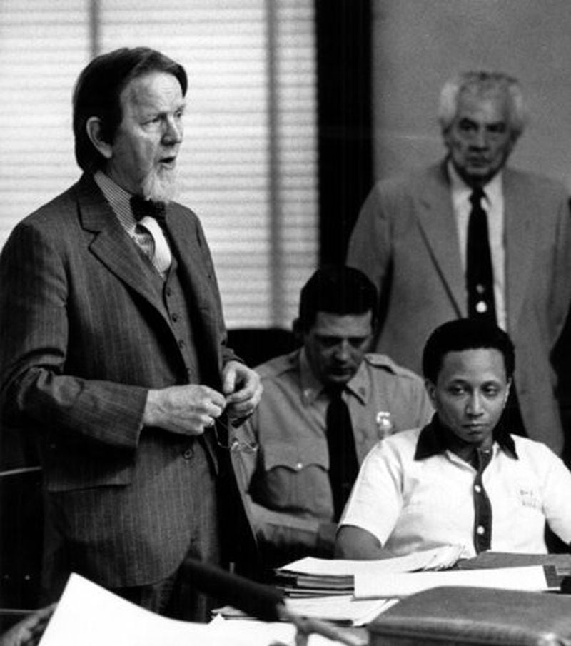 Wayne Williams, habillé en blanc de prison, regarde l'avocat Bobby Lee Cook se tenir debout pour plaider sa cause lors d'une audience de nouveau procès en 1986.