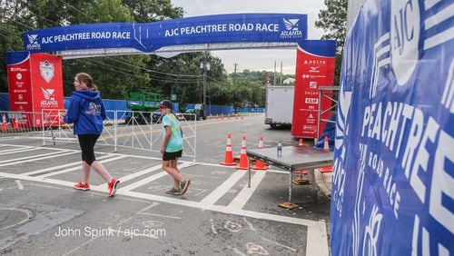 Mackenzie and Addison Brawner help set up Monday at the finish line of The Atlanta Journal-Constitution Peachtree Road Race at Piedmont Park. Thousands of runners will hit the pavement Tuesday. JOHN SPINK / JSPINK@AJC.COM