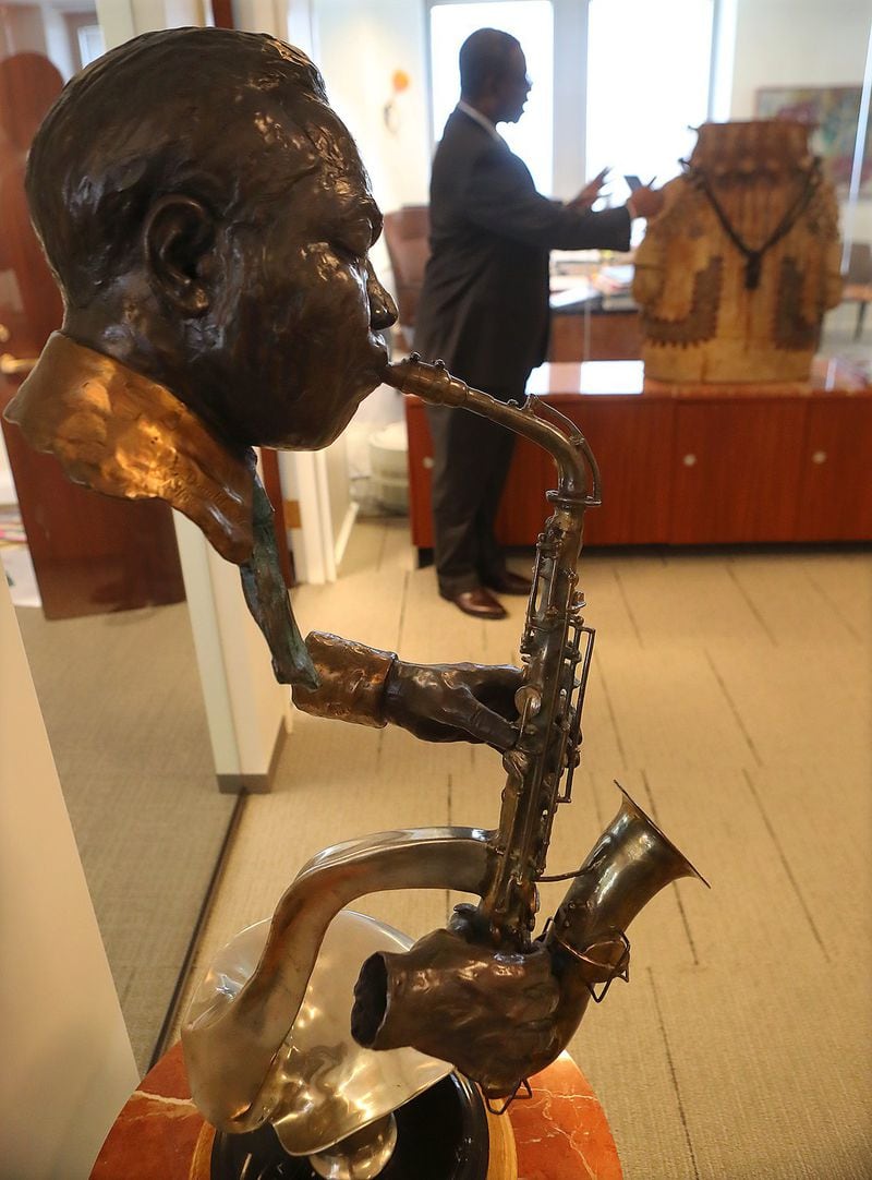 President & CEO Geoffrey Nnadi gives a tour of the Atlanta Life Financial Group art collection in the company office in June. The collection includes this plated bronze sculpture of Charlie Parker by Ed Dwight. Curtis Compton / ccompton@ajc.com