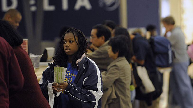 Delta passengers check their bags and pick up their tickets at the counter at Hartsfield-Jackson International Airport. Several airlines have added fees for checked luggage.