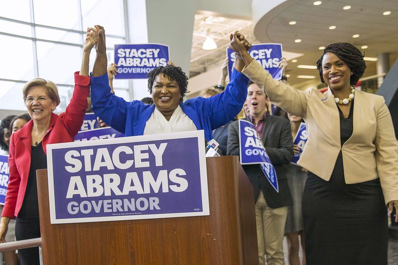 Democratic gubernatorial candidate Stacey Abrams links hands with U.S. Sen. Elizabeth Warren of Massachusetts (left) and Democratic congressional candidate Ayanna Pressley (right) during a rally at Clayton State University in Morrow on Tuesday. ALYSSA POINTER/ALYSSA.POINTER@AJC.COM