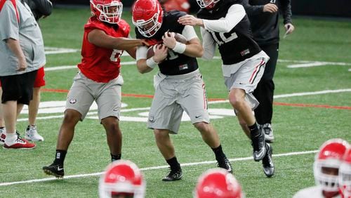 Georgia players, including  quarterback Jake Fromm (11) (with balls) during drills at practice today. Georgia traveled back to its indoor facilities in Athens two days before the national title game against Alabama in January. The indoor facility is expected to be named after former UGA player and Augusta National chairman Billy Payne.