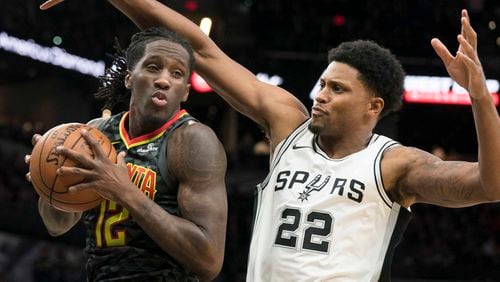 Atlanta Hawks forward Taurean Prince (12) looks to pass as he is guarded by San Antonio Spurs forward Rudy Gay during the first half of an NBA basketball game, Monday, Nov. 20, 2017, in San Antonio. (AP Photo/Darren Abate)