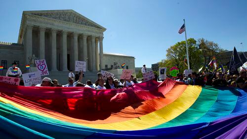 FILE - In this April 28, 2015, file photo, demonstrators stand in front of a rainbow flag of the Supreme Court in Washington, as the court was set to hear historic arguments in cases that could make same-sex marriage the law of the land. Gay and lesbian couples could face legal chaos if the Supreme Court rules against same-sex marriage in the next few weeks. Same-sex weddings could come to a halt in many states, depending on a confusing mix of lower-court decisions and the sometimes-contradictory views of state and local officials. Among the 36 states in which same-sex couples can now marry are 20 in which federal judges invoked the Constitution to strike down marriage bans. (AP Photo/Jose Luis Magana, File)