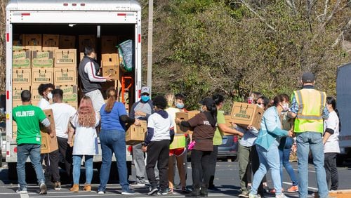Volunteers load a U-Haul with boxes of food heading for 
GIVE Center East school Saturday in Norcross on November 21, 2020.   STEVE SCHAEFER / SPECIAL TO THE AJC 
