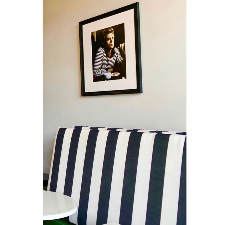 James Dean in stripes sits above a cafe banquette.