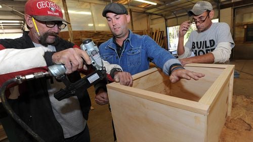 Brian Preston (center) with former workers Roger "TC" Curtis  and Carl A Carlson as they assemble a piece of furniture.  Staff file photo