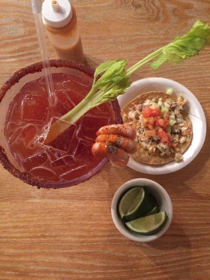 At Mariscos La Riviera Nayarit in Norcross, everyone gets a complimentary seafood tostada (right). Micheladas (left) are fishbowl size; the Michelada Nayarit is garnished with peeled shrimp and comes with two tiny oysters floating in the goblet. CONTRIBUTED BY WENDELL BROCK