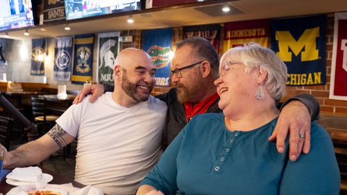 Bartender Dan Bergman (center) greets Kevin Gilliam and Joy Ivemeyer at the Woofs Sports Bar, one of many area restaurants that are becoming affectionately known as the Atlanta versions of "Cheers" due to a family friendly atmosphere and a growing sense of community. Photo by Ben Gray for The Atlanta Journal-Constitution