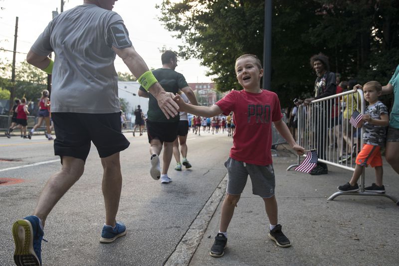 Six-year-old Jack Mearman encourages runners during the 49th running of the AJC Peachtree road race near Piedmont Park, Wednesday, July 4, 2018.  ALYSSA POINTER/ALYSSA.POINTER@AJC.COM