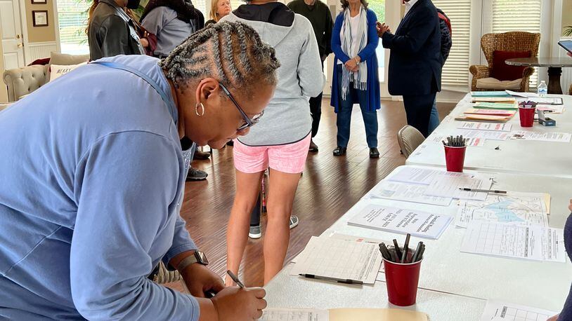 Resident Stacey Walker signs a petition to de-annex from the city of Mableton at a signing event January 7, 2023, in Mableton while other residents talk with state Rep. David Wilkerson. Photo provided
