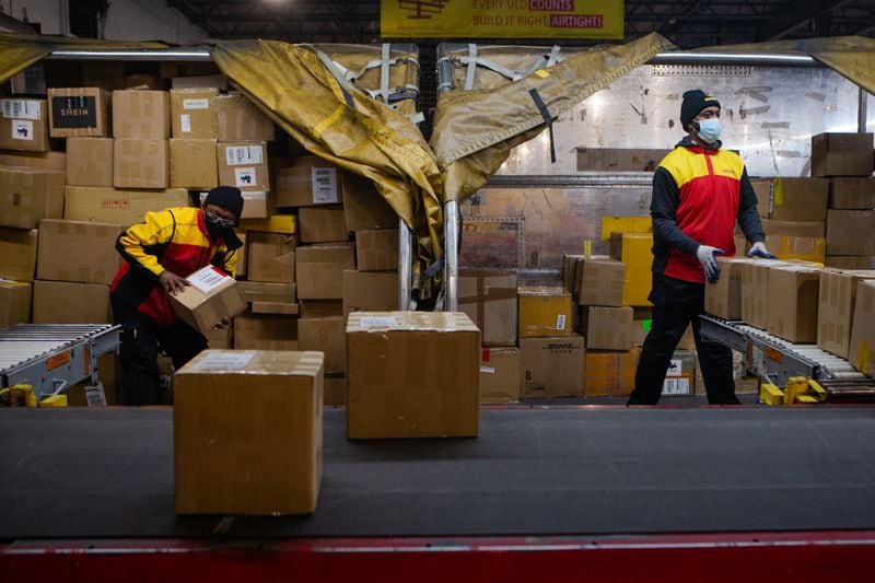 Willie Gurerra (left) and Milton Jones (right) sort packages on Wednesday, December 16, 2020, at DHL Express in Atlanta. Workers at the shipping center worked to fulfill orders during the holiday rush. CHRISTINA MATACOTTA FOR THE ATLANTA JOURNAL-CONSTITUTION.