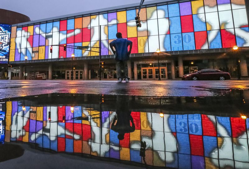 June 22, 2017 Atlanta: Kenny Brown walks by the pooling water from rain reflected the colorful facade of the College Football Hall of Fame at 250 Marietta St NW, in downtown Atlanta on Thursday, June 22, 2017.  JOHN SPINK/JSPINK@AJC.COM.