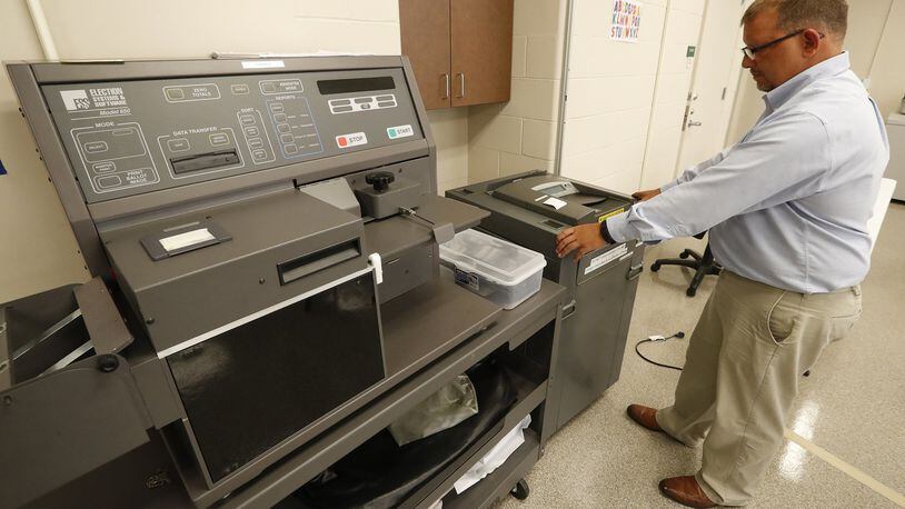 Jason Baker, the director of the Clark County Board of Elections, pulls out one of the portable voting machines that are placed in election polls and puts it next to the high-speed voting machine that’s used to count absentee ballots at the Board of Elections office on Aug. 31, 2017. Both machines are about 15 years old and require regular maintenance. Bill Lackey/Staff