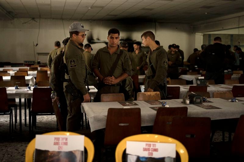 Israeli soldiers look at chairs for hostages held in Gaza at a Passover Seder table on Thursday, April 11, 2024, at the communal dining hall at Kibbutz Nir Oz in southern Israel, where a quarter of all residents were killed or captured by Hamas on Oct. 7, 2023. For many Jews, no matter how observant, Passover is a time to unite with family to eat and drink around what's known as a Seder table, remembering how the Jews persevered through harsh times. But this year, when Passover begins on Monday, many families are torn on how to celebrate, or if it's worth acknowledging at all. (AP Photo/Maya Alleruzzo)