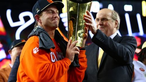 College Football Playoff Executive Director Bill Hancock presents the trophy to the Clemson Tigers head coach Dabo Swinney.