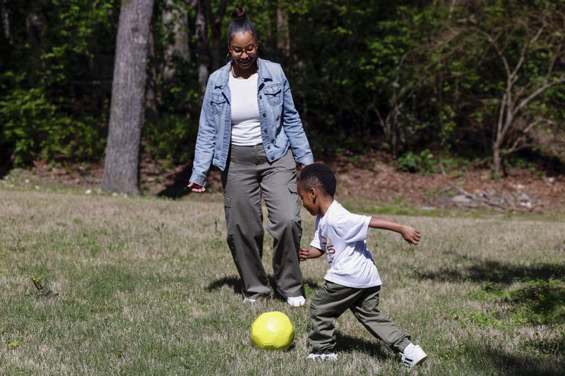Adriane Burnett plays soccer with her son Karter Robinson on Saturday, April 14, 2024 in Birmingham, Ala. Women's participation in the American workforce has reached a high point, but challenges around child care are holding back many working class parents. When women without college degrees face an interruption in child care arrangements – whether it's at a relative's home, a preschool or a daycare center – they are more likely to have to take unpaid time or to be forced to leave their jobs altogether, according to an Associated Press analysis. (AP Photo/Butch Dill)