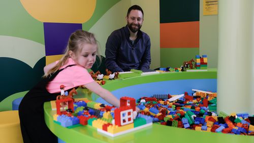 Mike Tavani watches his daughter Vienna, 6, play in Duplo Park at Lego Discovery Center Atlanta in Phipps Plaza on Friday, March 31, 2023. After six months of renovations, the attraction opened with upgrades and new additions. (Natrice Miller/natrice.miller@ajc.com)