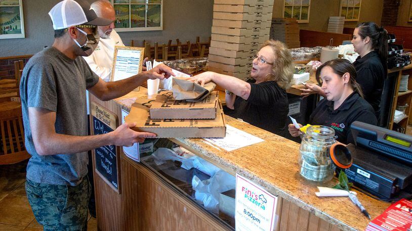 Steve Pifer (L) picks up an order of pizza at Fini’s Pizzeria on a Friday night in Lawrenceville. STEVE SCHAEFER / SPECIAL TO THE AJC